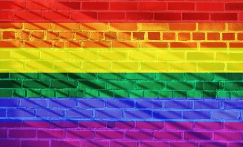 Rainbow Pride Flag projected on a sunny brick wall background Illustrazione stock