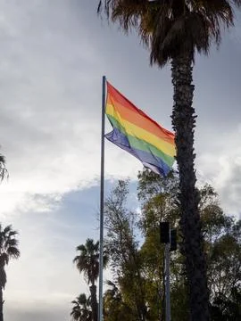 Rainbow Pride flag waving on flagpole against clear blue sky Stock Photos