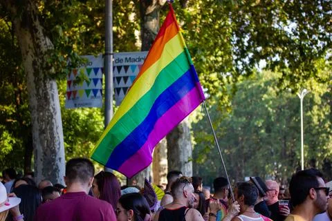 A rainbow pride flag waving over a dense crowd of participants Pride parade 库存照片