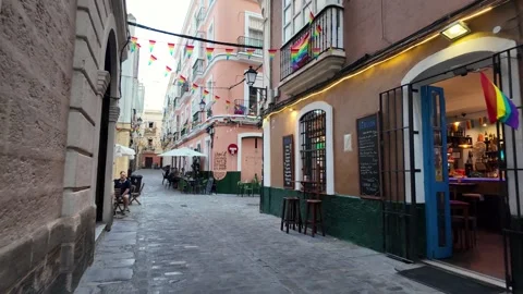 Rainbow pride flags hanging across narrow street, El Populo, Cadiz, Spain Stock Footage 341624134