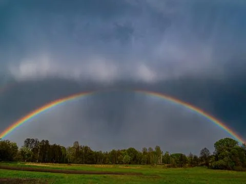 Rainbow with rain clouds in the sky. Stock Photos
