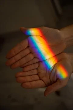 Rainbow ray on a woman's hand. Stock Photos