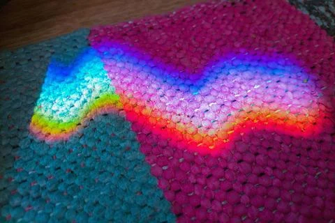 Rainbow reflection from mirror on full carpet. Interference of sunlight, sc.. Stock Photos