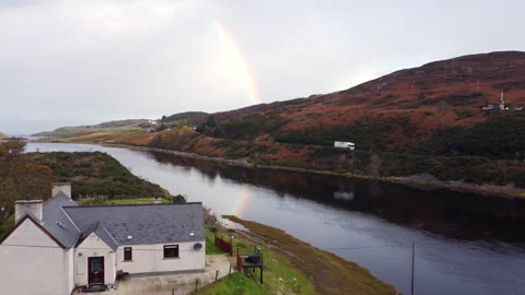 A rainbow reflects on a river next to a house Stock Footage 258282761