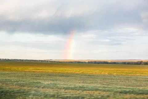 A rainbow is in the sky above a field Foto stock