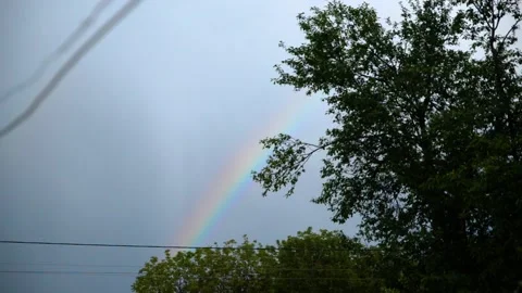 Rainbow in the sky against a background of dark clouds on a summer evening Stock Footage 132711913