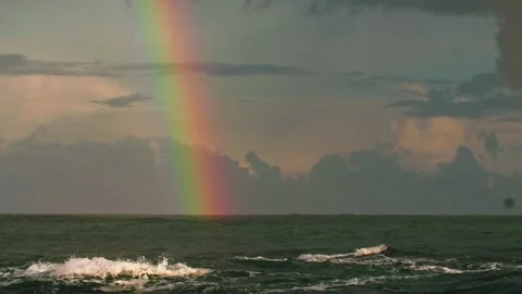 A rainbow in the sky with clouds after a storm over a rough sea. Long shot taken Stock Footage 217727962