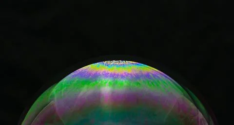 Rainbow soap bubble on a black background close-up. Stock Photos