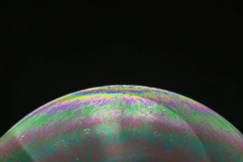 Rainbow soap bubble on a black background close-up. Stock Photos