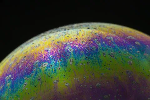 Rainbow soap bubble on a black background close-up. Stock Photos