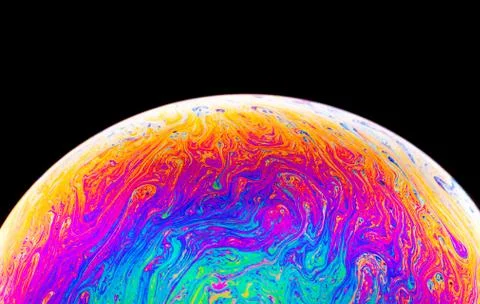 Rainbow soap bubble on a dark background. Close-up of colorful surface. Stock Photos