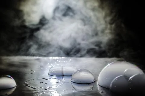 Rainbow soap bubbles on a dark background. Abstract wet surface with fog and  Stock Photos