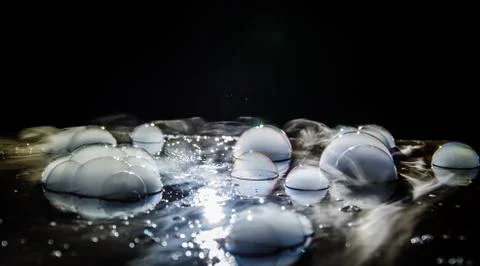 Rainbow soap bubbles on a dark background. Abstract wet surface with fog and  Stock Photos