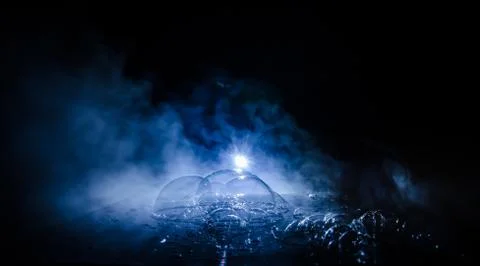 Rainbow soap bubbles on a dark background. Abstract wet surface with fog and  Stock Photos