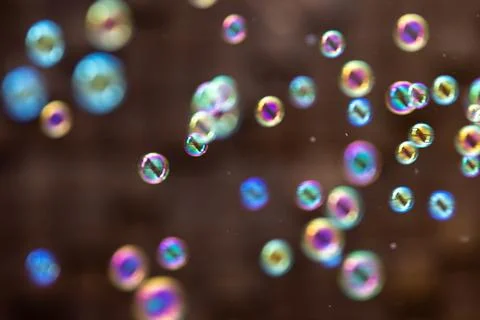 Rainbow soap bubbles floating on dark backdrop. Colorful summer background .. Stock Photos