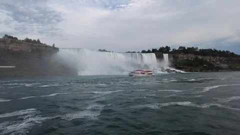 A rainbow in the spray of American Falls as a tour boat crosses the Niagara Stock Footage 345996052