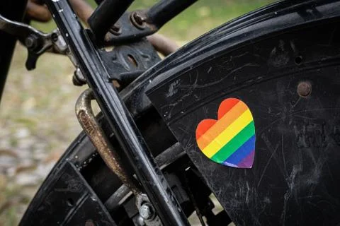 Rainbow sticker in shape of a heart on old black bicycle Stock Photos