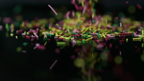 Rainbow sugar sprinkles start fall and scattering. Slow motion black background Vídeos de archivo 283657511