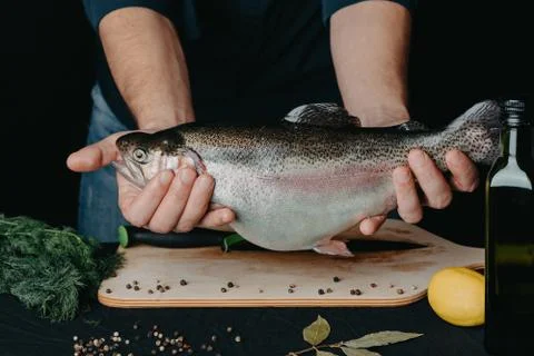 Rainbow trout hands chef close-up over the Board spices Stock Photos