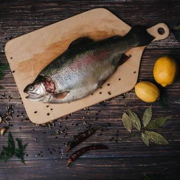 Rainbow trout lying on Board with spices Stock Photos