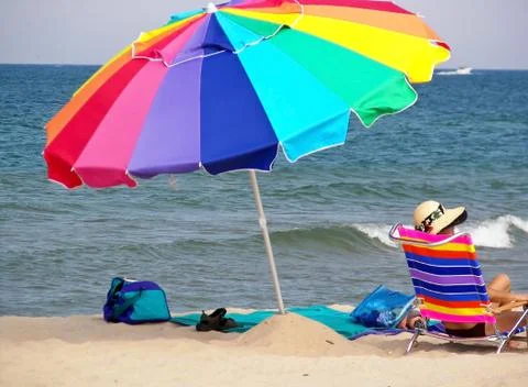 Rainbow umbrella with sunbather Stock Photos