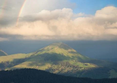 Rainbow under mountains at the rain Stock Photos