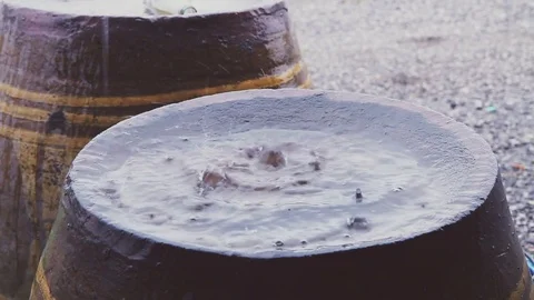 Raindrop falling to bottom of big earthen jar Stock Footage