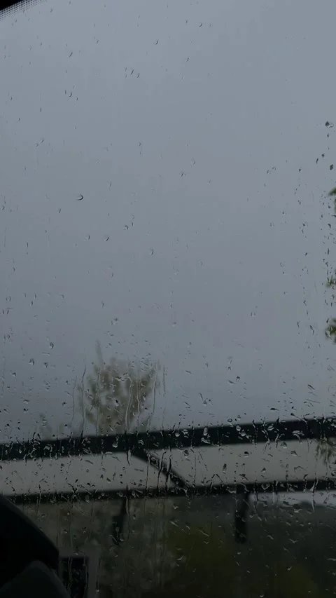 Raindrop, flowing down clear window glass, blurs exterior, displaying an Video stock 333163799