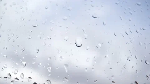 Raindrop rolls down a window glass against cloudy sky background Stock Footage 169586929