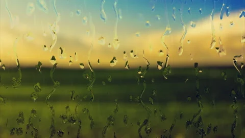 Raindrop trickles down a wet window during a rainstorm over a field Stock Footage 321545163