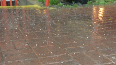 Raindrops and hail fall on the paved sidewalk	 Vídeo Stock 105344621