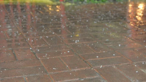 Raindrops and hail fall on the paved sidewalk	 Vídeos de archivo 105344746