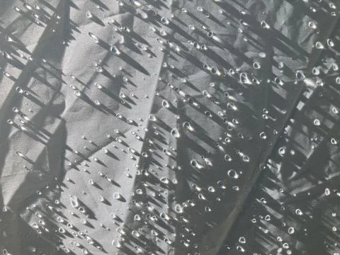 Raindrops and their shadow on plain white canvas fabric Stock Photos
