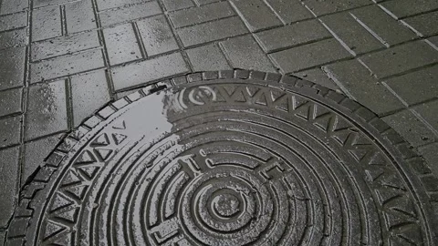 Raindrops are falling on the manhole cover on a cloudy day. Stockbeeldmateriaal 275924193