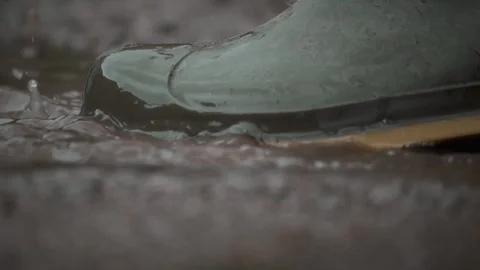 The raindrops are rhythmically splashing on the rain boots while creating Stock Footage 310169604