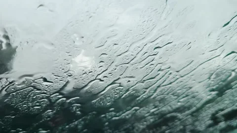Raindrops are seen on a vehicle's windshield, creating an abstract water patt Stock Footage 323394526
