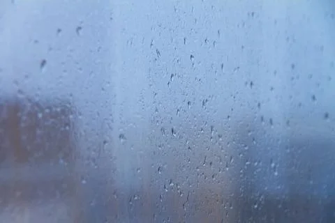 Raindrops on blue glass window on cloudy day Stock Photos