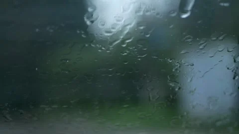 Raindrops blur the view as they slide down the window, intermittently clear.. Video stock 255277876