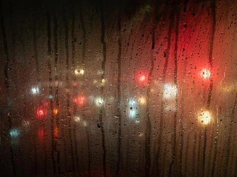 Raindrops on a bus window with blurred headlights behind Foto stock