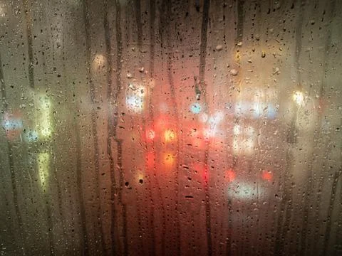 Raindrops on a bus window with blurred headlights behind Stock Photos