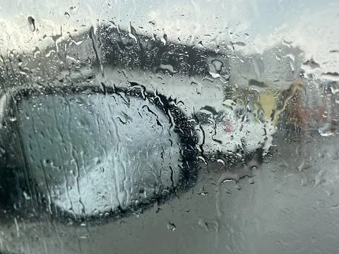 Raindrops on the car window on the background of the mirror Stock Photos