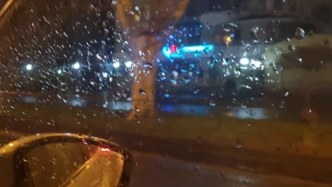 Raindrops on car window during night drive through city streets. Stock Footage 306168967