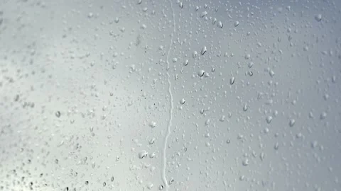 Raindrops cascade down a window in stunning close-up Stock Footage 295977647