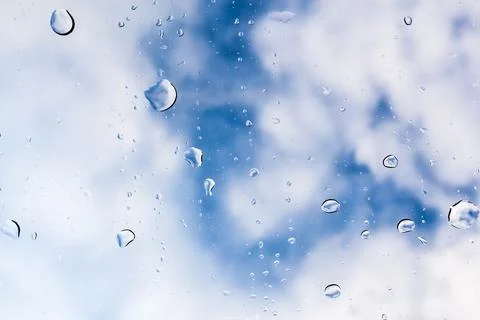 Raindrops cling to a window with a backdrop of blue sky and clouds in a serene Stock Photos