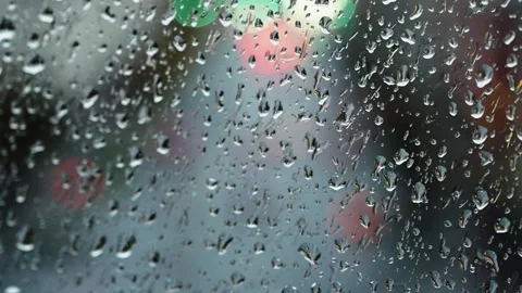 Raindrops clinging to a windowpane with soft bokeh from out-of-focus traffic Stock Footage 327322835
