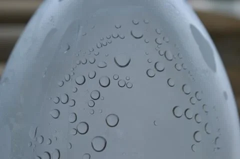 Raindrops collect on a smooth surface while reflecting light in a serene outdoor Stock Photos