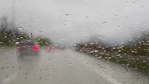 Raindrops cover a windshield while driving on a rainy highway Vidéo 310335160
