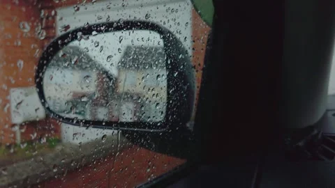 Raindrops covering parked car side mirror near quiet suburban street during Stock Footage 335144164