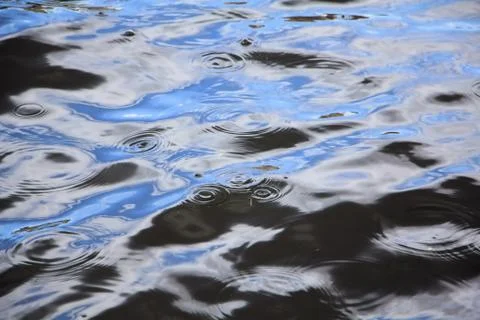 Raindrops create circular waves on the waves of the river Stock Photos
