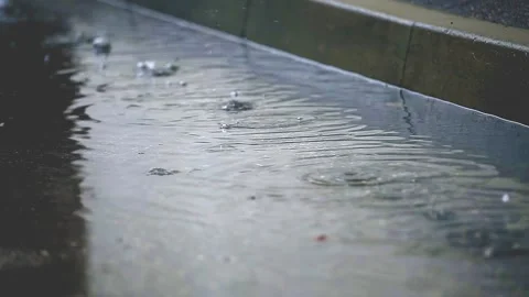 Raindrops drip into a puddle on the sidewalk. The concept of rain, thaw Stock Footage 153380268